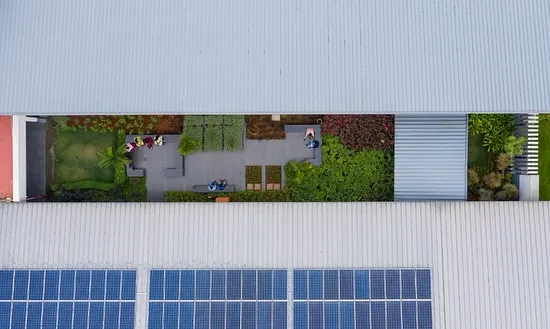 This aerial view of a factory extension shows my commitment to energy efficiency, with integrated solar panels and a green roof. The central courtyard is a landscaped breakout space, improving the indoor environment for workers.