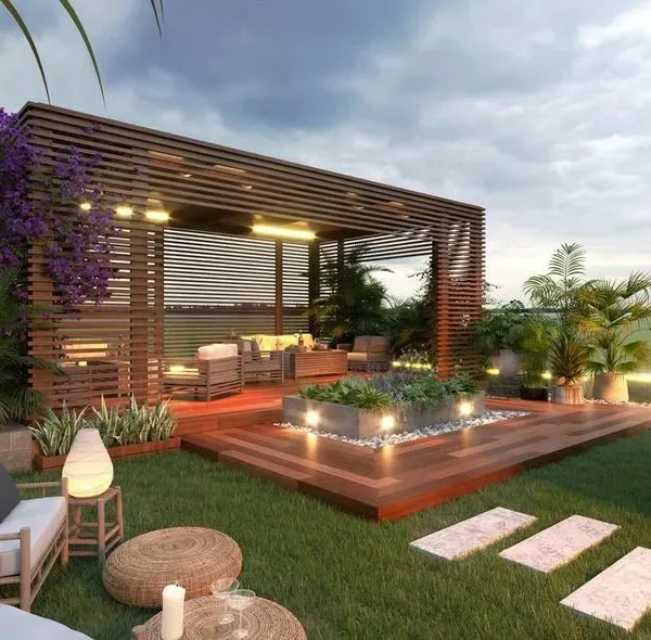 I design and build complete outdoor living spaces, like this rooftop terrace featuring a modern wooden pergola, integrated lighting, and comfortable seating areas surrounded by lush greenery.