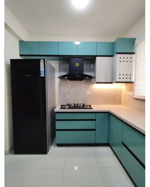 A complete view of the U-shaped kitchen in #TheDivinityHome. The layout is designed for efficiency, with the stove, sink, and refrigerator forming a perfect work triangle. The teal and white cabinetry adds a fresh, modern look.