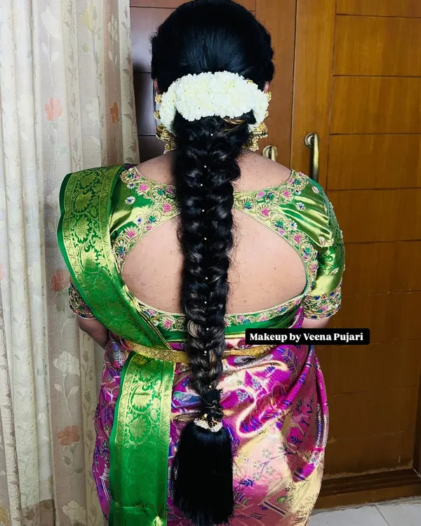 A classic South Indian bridal braid, neatly woven and decorated with traditional pearl accessories. This style is elegant and perfectly complements a silk saree.