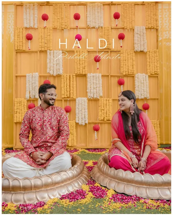 A happy couple seated in lotus-shaped pots during their 'phoolon ki haldi'. This shot captures the unique decor and joyful traditions of a modern haldi ceremony.