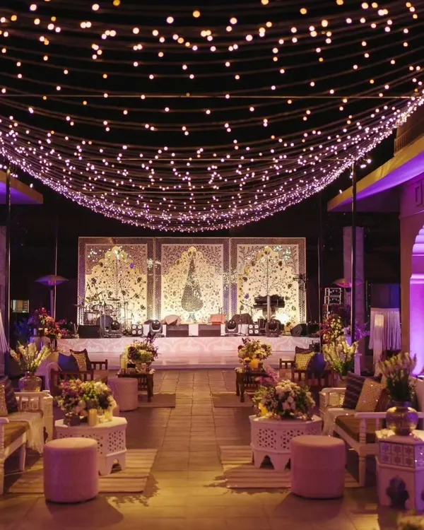 The entrance to a Sufi Night, featuring a canopy of fairy lights over a lounge-style seating area. The design uses white and lavender tones to create a serene and mystical vibe.