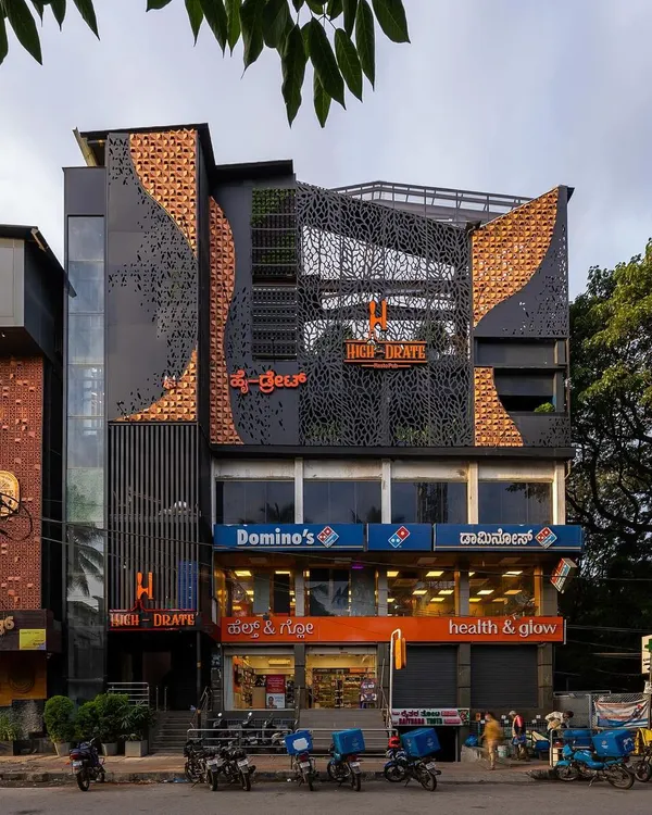 The completed facade transformation for 'High-drate' restopub. The new design uses a dynamic mix of materials including brick, perforated metal screens, and integrated greenery to create a bold, contemporary identity.