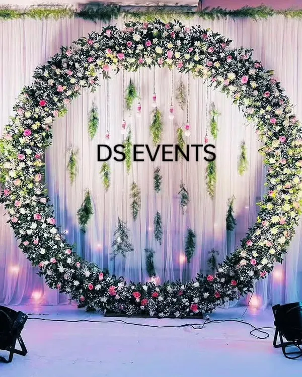 This circular floral arch is one of my most requested designs for receptions and engagements. I use a mix of fresh flowers and foliage against a soft white drape, complemented by professional lighting to create a romantic and picture-perfect backdrop.