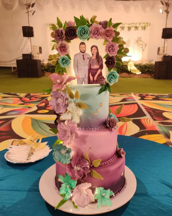 Baking for family is a special kind of pressure and pleasure. This two-tiered wedding cake, with its custom couple topper and cascade of handmade sugar flowers in shades of purple and teal, was an honor to create for my nephew and his bride.