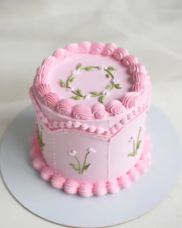 Isn't she lovely? This vintage-style cake features intricate piping, delicate floral details, and a unique hexagonal shape, all in a beautiful shade of pink. Inside is a rich Bailey's Chocolate flavor.