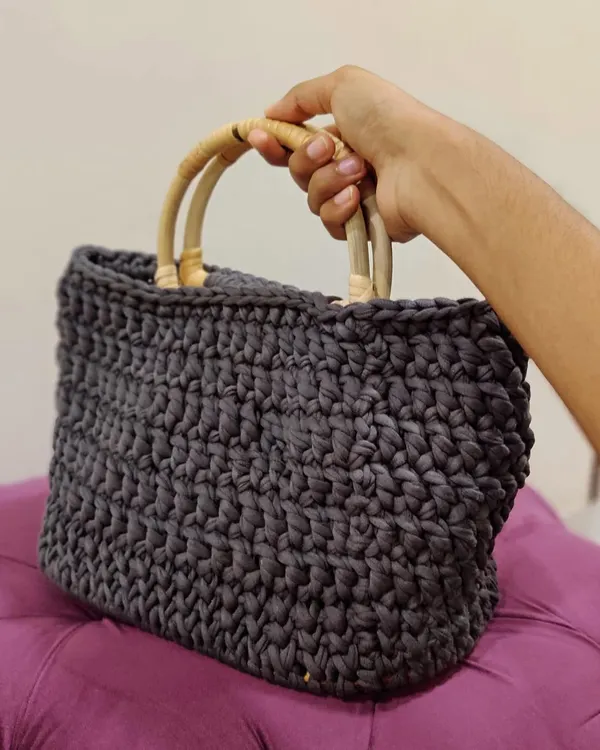 This T-shirt Yarn Basket Bag is made from chunky yarn, giving it a sturdy structure. It features a wooden base and smooth bamboo handles, perfect for carrying your daily essentials.