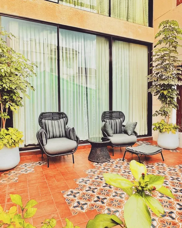 This intimate patio corner features comfortable seating on a bed of vibrant, patterned terracotta tiles. The design blends traditional Moroccan aesthetics with modern comfort, creating a cozy nook for relaxation.