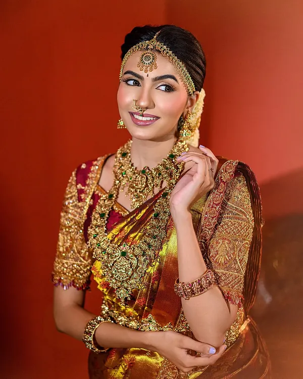 This is a signature Muhurtham look we created, focusing on a radiant bridal glow. I used soft lighting to complement the intricate gold jewelry and the rich texture of the silk saree, capturing a moment of serene happiness.