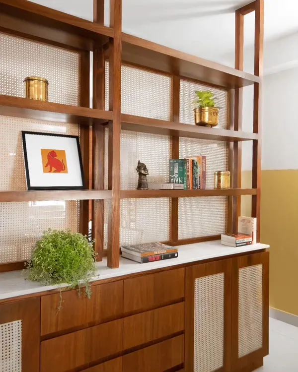 The foyer cabinet was custom-designed with teak wood and woven cane panels. It provides storage while acting as a semi-transparent visual screen, defining the entryway without enclosing it.