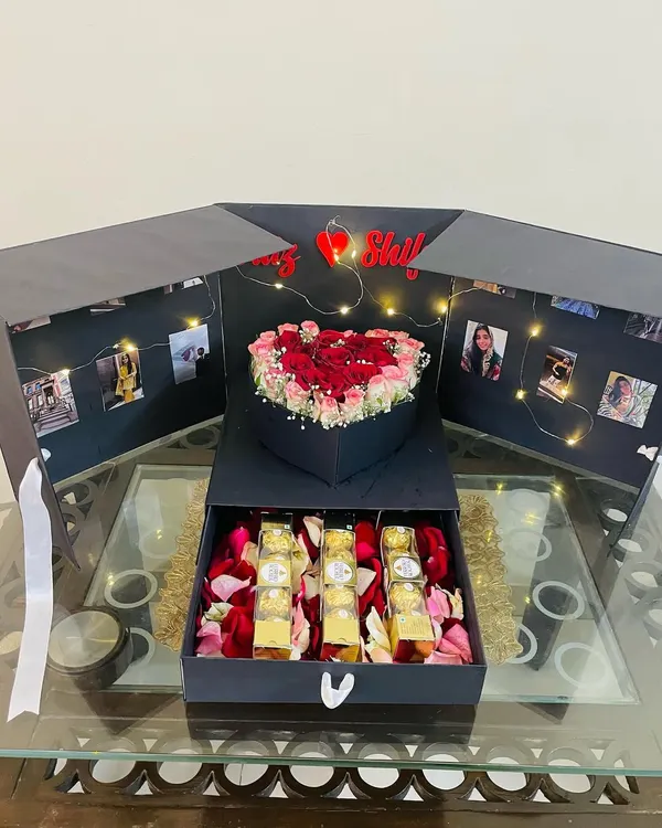 This is our signature showstopper, the surprise explosion box. When you lift the lid, the sides fall away to reveal a heart-shaped floral arrangement, a string of fairy lights illuminating personal photos, and a hidden drawer filled with Ferrero Rocher chocolates. It's the ultimate personalized gift for an anniversary or birthday.