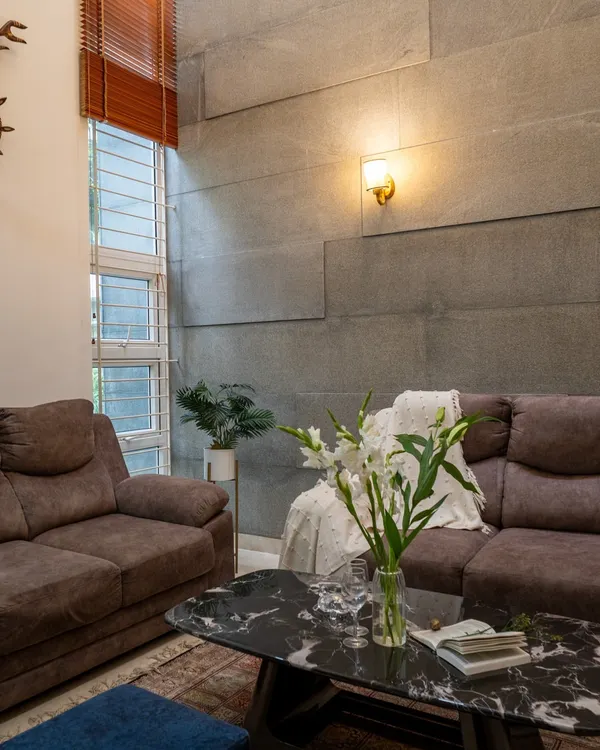 A double-height ceiling allows for dramatic design elements, like this textured grey panel wall, which adds depth and character to the living space.