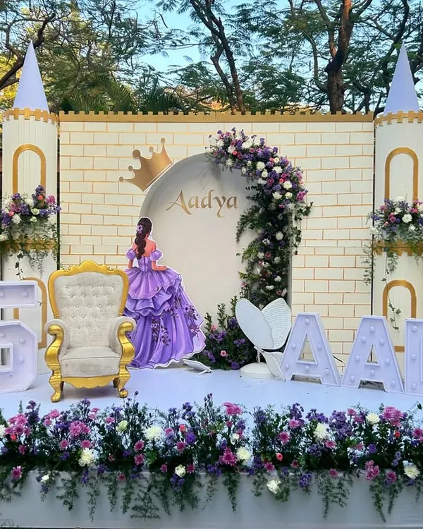 A beautiful Sofia the First themed 5th birthday party, featuring a full castle facade, a golden throne for the birthday girl, and large light-up letters spelling her name.