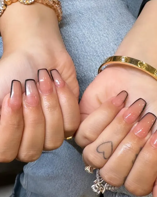 A chic and modern take on the French manicure. These long coffin nails have a sheer nude base with a sharp, thin black outline instead of a classic white tip.