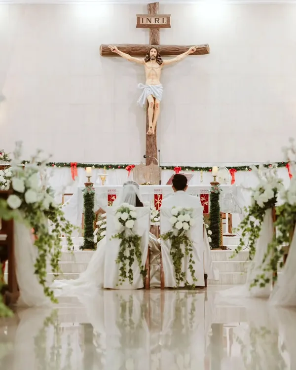 A powerful and serene moment as Ryan and Ela kneel before the altar. The decor is intentionally kept elegant and minimal with white florals, ensuring the focus remains on the sanctity of their vows and the beautiful church architecture.
