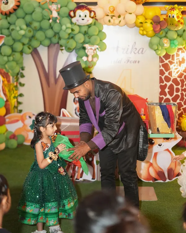 A magician captivates the birthday girl during her jungle-themed party. Live entertainment like a magic show is a fantastic way to keep all the young guests mesmerized.
