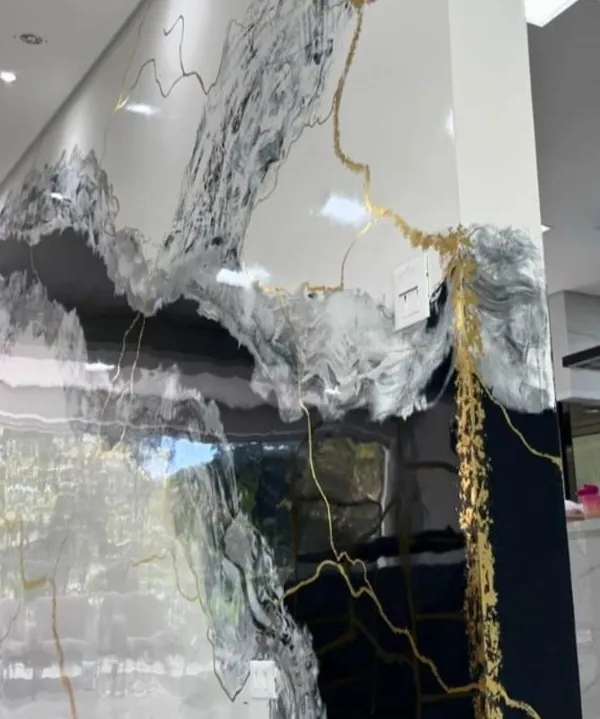 A luxurious, high-gloss marble effect painted directly onto the wall, featuring dramatic black and gold veins. This is a premium finish for a sophisticated living or commercial space.