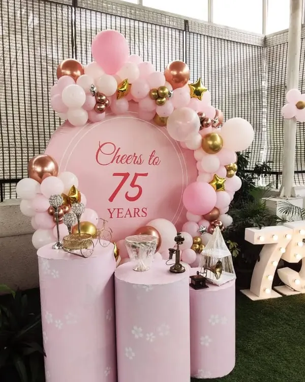 A beautiful 'Cheers to 75 Years' celebration, designed with a soft pink color scheme, elegant plinths, and a lovely balloon garland.