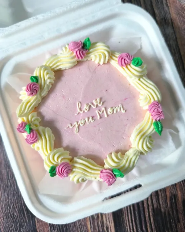 A beautiful and classic bento cake for Mom. This design features a wreath of piped buttercream roses and leaves surrounding a heartfelt message in delicate script.
