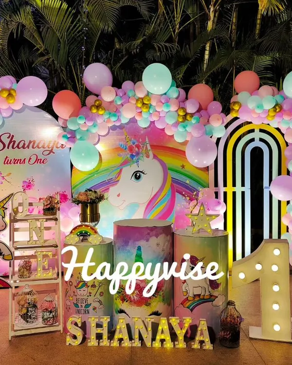 A magical unicorn party for Shanaya's first birthday. The setup is full of pastel rainbows, unicorn cutouts, and a large light-up number "1" for a truly enchanting celebration.