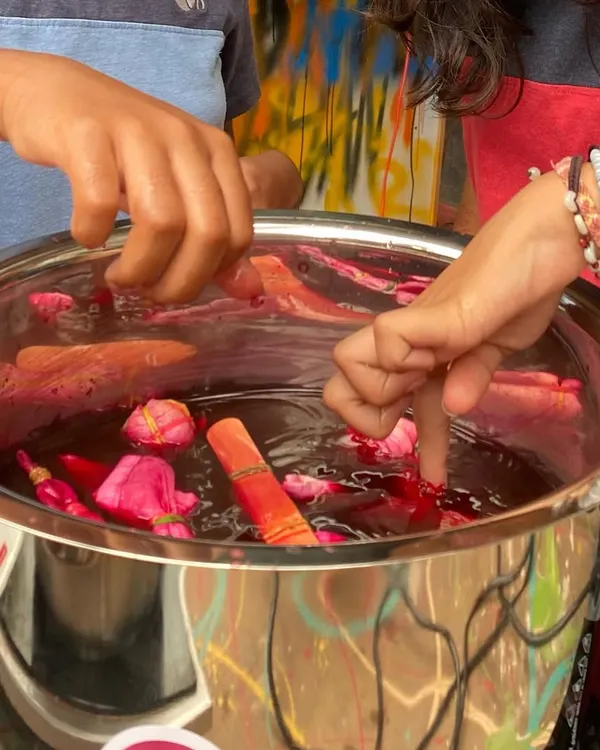 A close-up of our natural tie-dye workshop. Participants are dipping their bundled fabric into a dye bath made from natural ingredients. It is a magical process to watch the colours take hold.