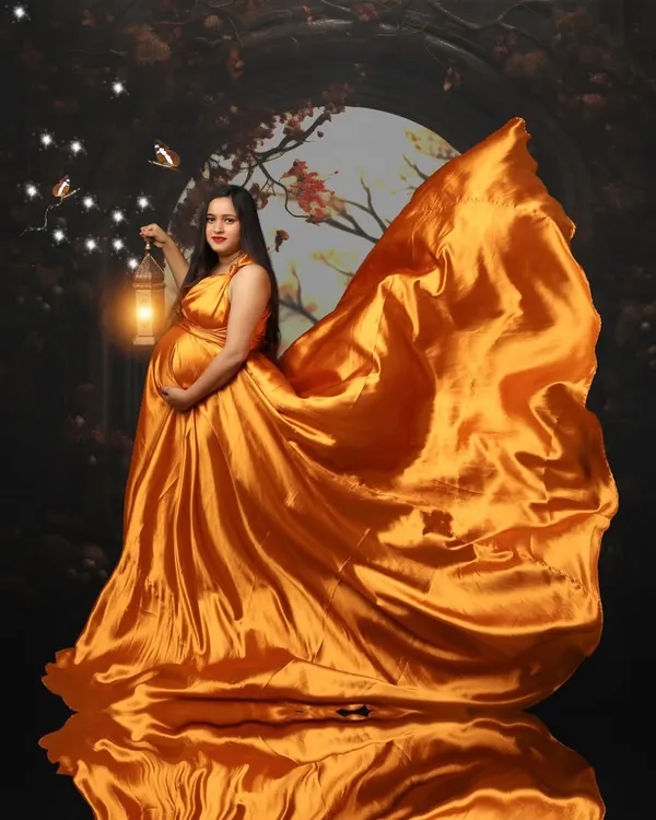 A mother's glow truly lights up the world. This portrait captures that magical feeling with a flowing golden gown and a lantern to guide the way, reflecting the beautiful journey of creating life.