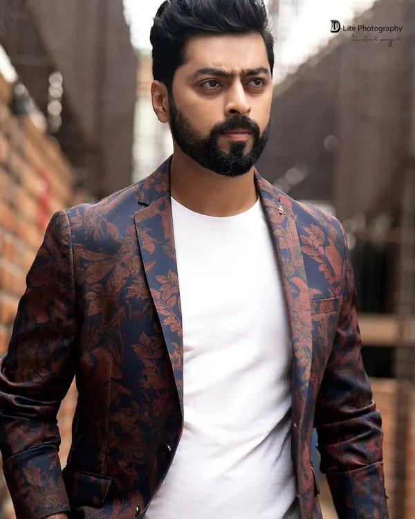A strong portrait of actor Tarak Ponnappa. The combination of a floral blazer, a simple white tee, and a gritty urban background creates a modern and stylish look.