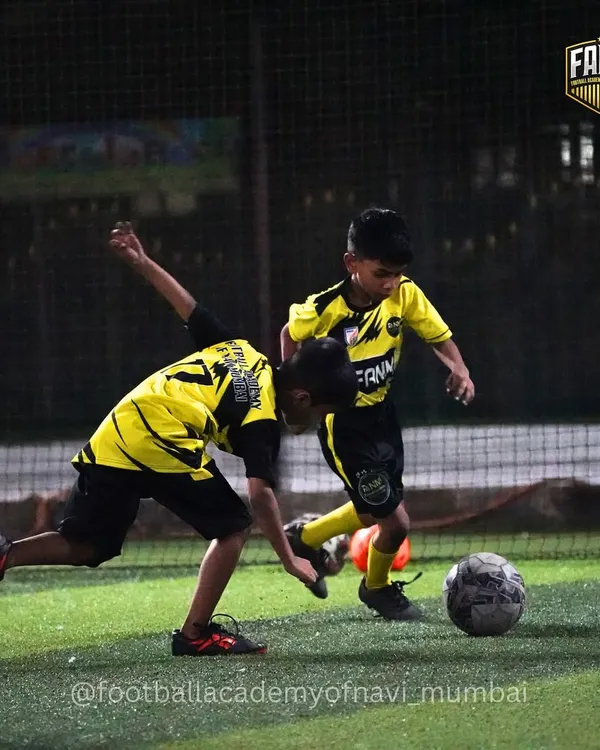 Two young players battle for the ball in a practice match. I encourage healthy competition and teach players how to tackle fairly and effectively.