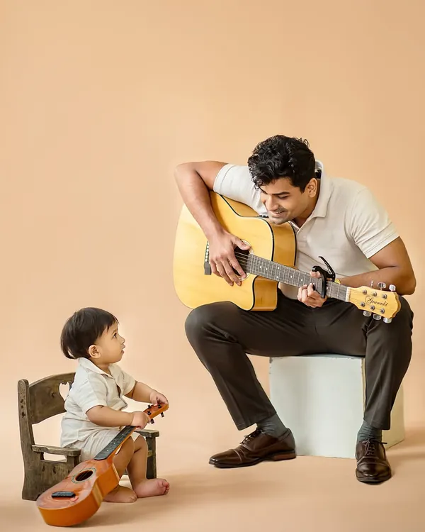 A heartwarming studio moment between an uncle and his nephew, sharing a love for music. The little one looks on in admiration, creating a beautiful, candid portrait.