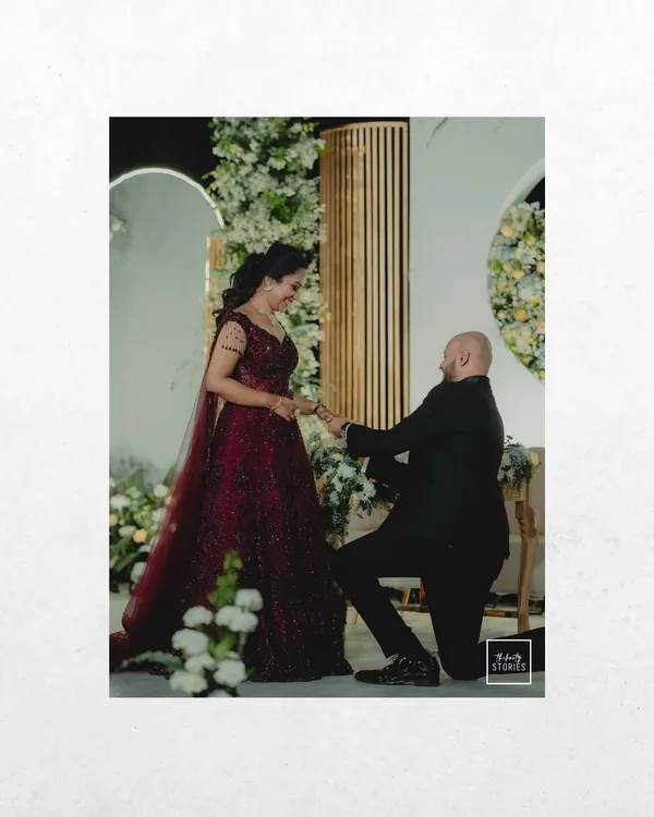 The classic proposal moment, captured forever. This shot focuses on the emotion and significance of the ring exchange during a beautifully decorated engagement event.