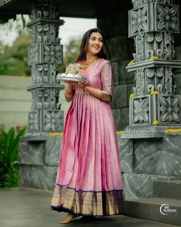 This flowy, floor-length gown was crafted from a client's treasured silk saree. I designed it with a fully pleated skirt to create beautiful movement, carefully preserving the original dark blue and gold border along the hemline.