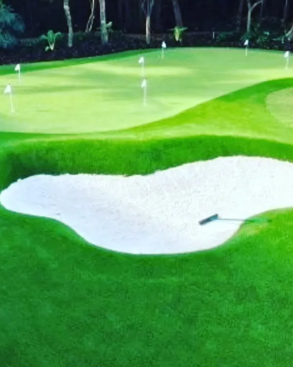 A custom putting green with a professionally installed sand trap. The deep bunker adds a challenge for your short game practice, surrounded by lush fringe turf.