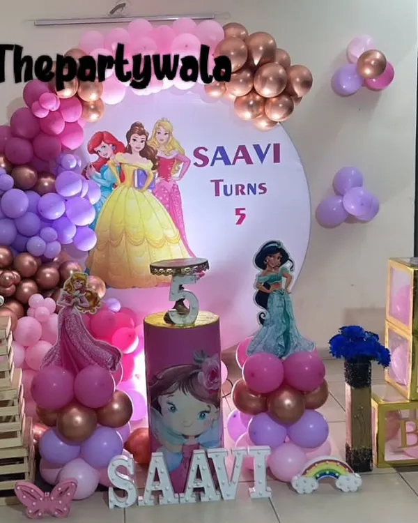 A grand princess party for Saavi's 5th birthday, featuring a backdrop with multiple Disney princesses. The purple, pink, and rose gold balloons, along with light-up "BABY" boxes, create a royal atmosphere.