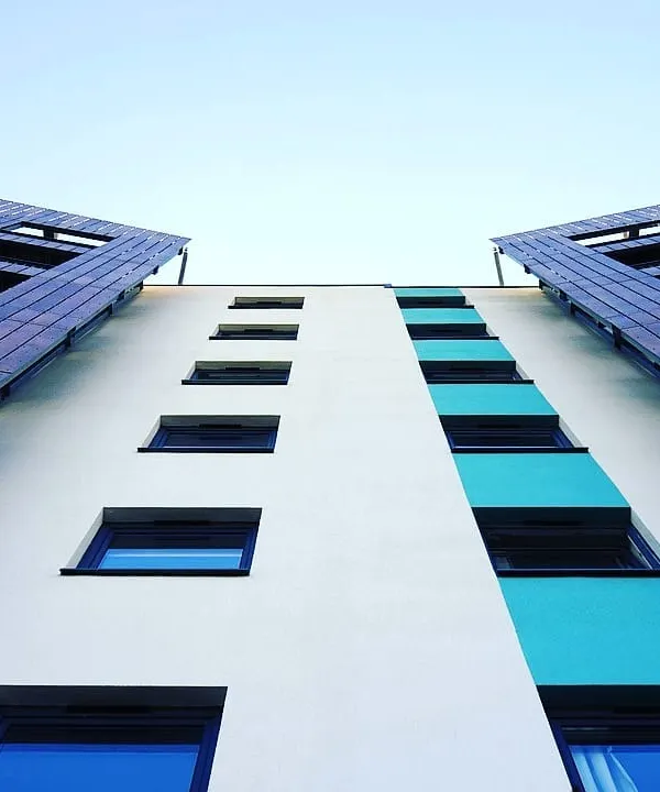 An upward view of a modern apartment building's exterior. I use high-quality exterior paints to create striking designs and protect the building from the elements.