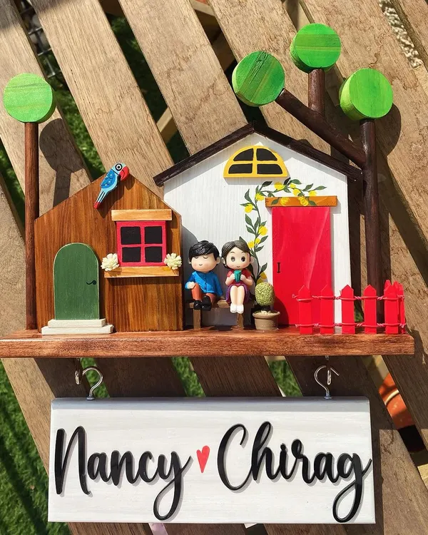 This is my top-selling diorama design, and it’s easy to see why. It features two little houses, a miniature couple, and vibrant, hand-painted details like the lemon vine and red fence. The hanging name board with hooks for keys makes it as functional as it is charming.