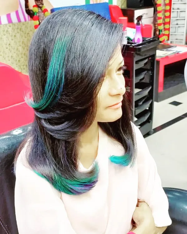 A pop of color can transform your entire look. Here, I've added vibrant teal and purple peekaboo highlights to a layered cut for a fun and edgy style.