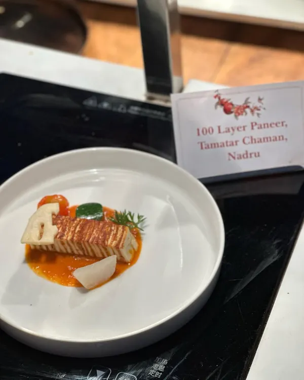 Our signature 100-Layer Paneer with Tamatar Chaman and Nadru. This dish is a testament to our technical skill, featuring paper-thin layers of cottage cheese in a rich, flavourful gravy.