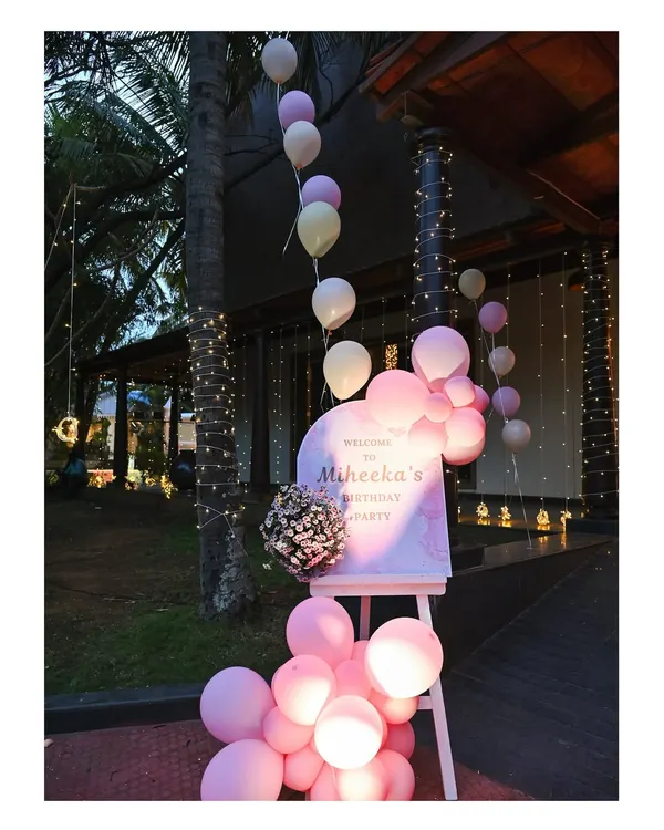 A beautiful evening entrance for Miheeka's birthday party. A personalized welcome sign is surrounded by illuminated pink balloons and twinkling fairy lights.