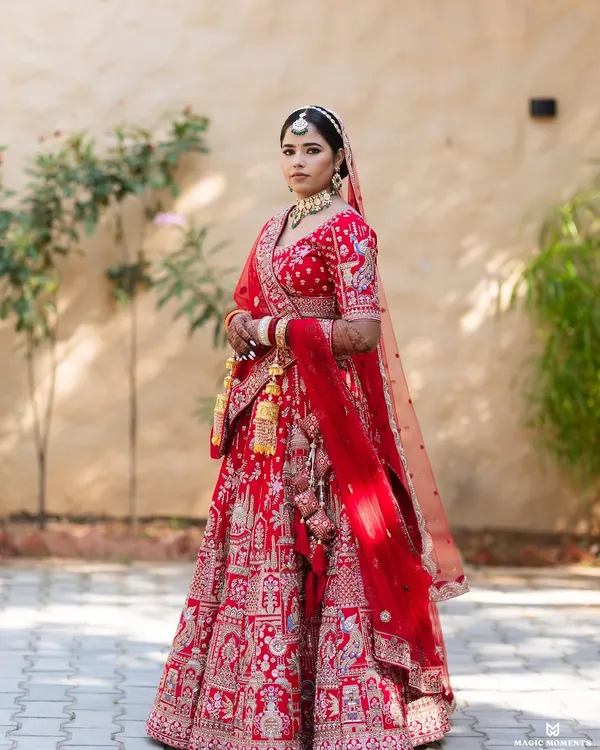 A stunning full-length portrait of the bride, Priya, in her magnificent red wedding lehenga. I focus on classic poses that highlight the beauty of the bridal attire.
