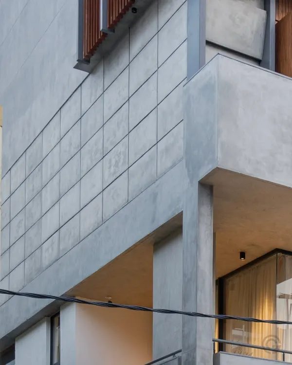 A detail of the exterior facade, showing the sharp lines of the concrete volumes. The grid-patterned concrete panels add texture and a sense of crafted detail to the brutalist-inspired form.