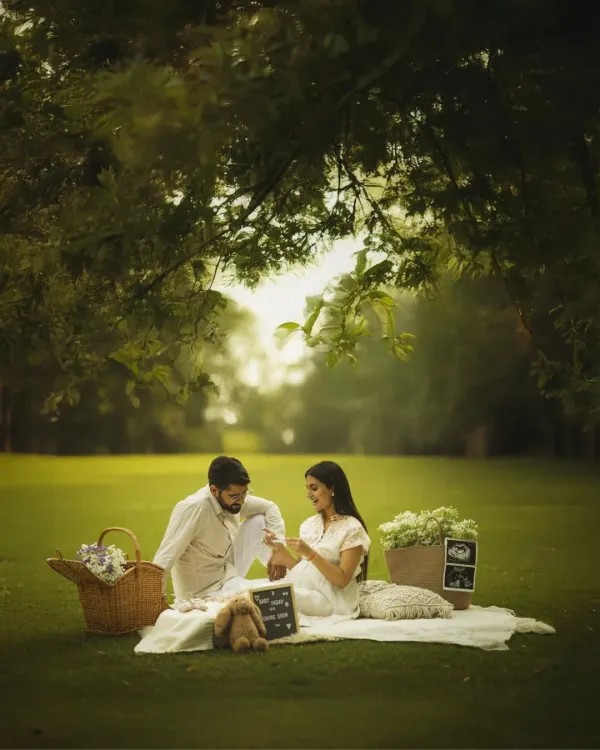 A perfect picnic for three. This beautifully styled outdoor scene, complete with a basket, flowers, and sonogram pictures, creates a charming and memorable setting for this couple's maternity shoot.