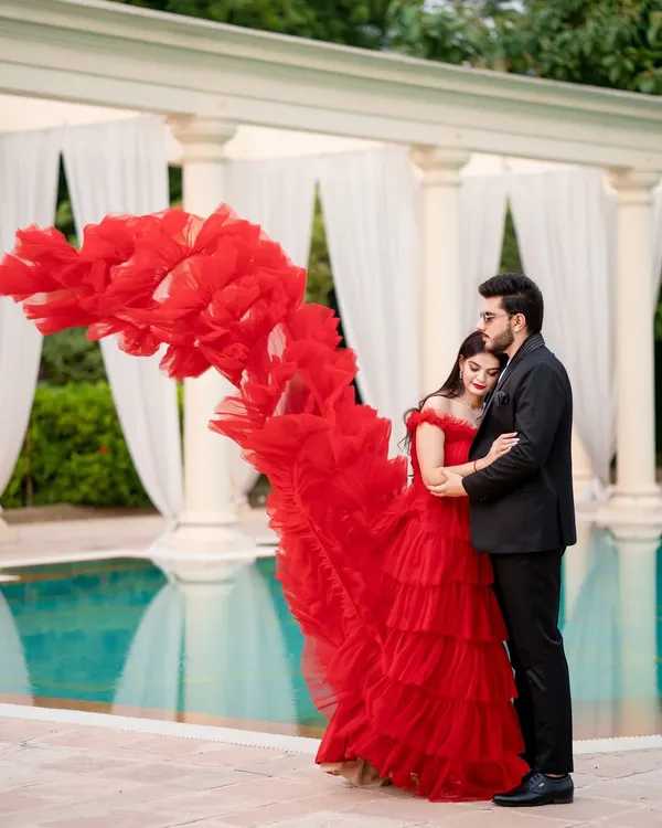 The magic of a flowing red gown. This shot is all about drama and elegance, with the dress creating a beautiful wave of color against the classic white columns and tranquil pool.