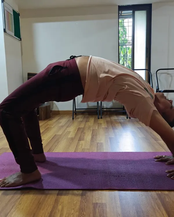 A student finds their arch in Chakrasana (Wheel Pose). This powerful backbend opens the heart, strengthens the arms and legs, and energizes the entire body.