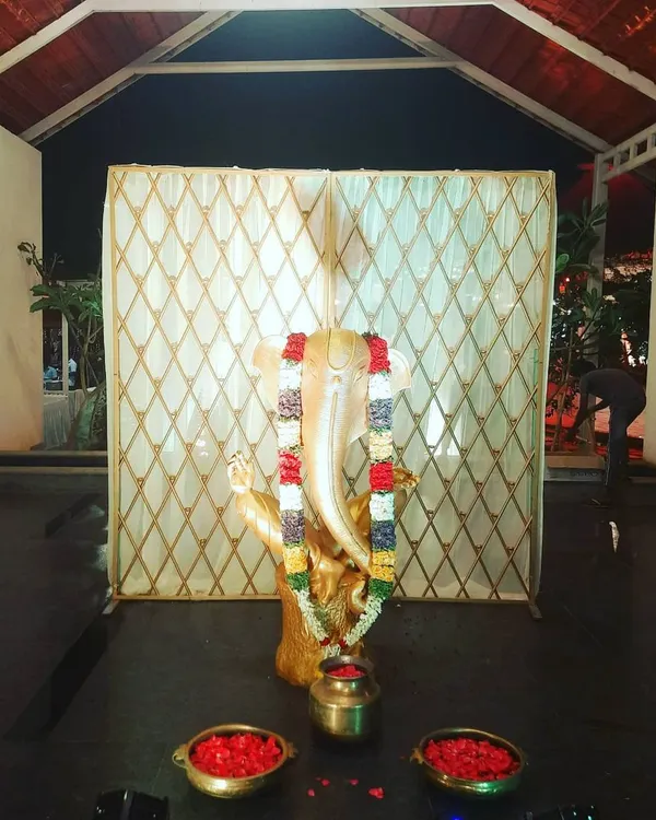 A Ganesha idol placed at the entrance of an event, set against a simple backdrop. This setup is ideal for welcoming guests and invoking blessings for a wedding or puja.