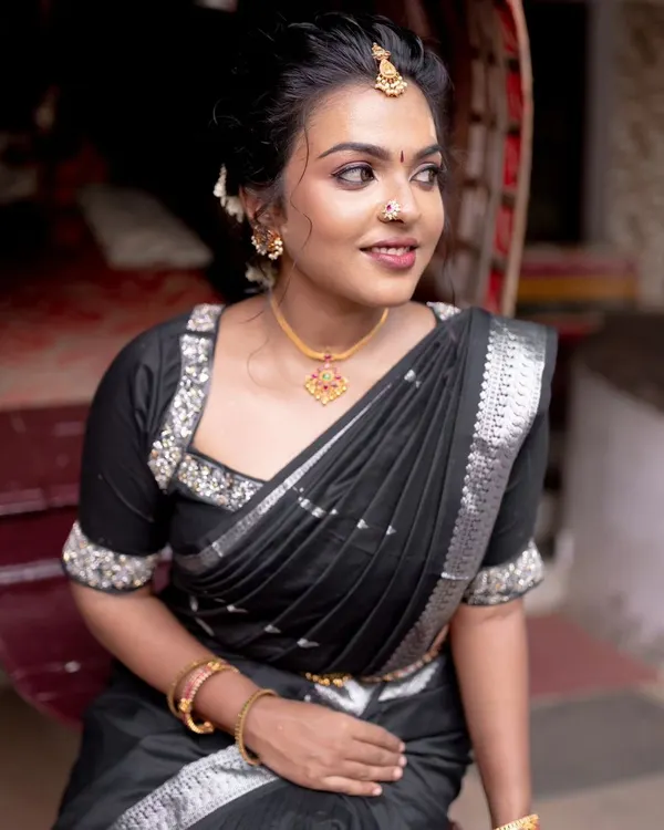 A bold and beautiful look for a model shoot. The black saree with silver accents is paired with a modern, chic hairstyle and makeup that highlights her strong features.