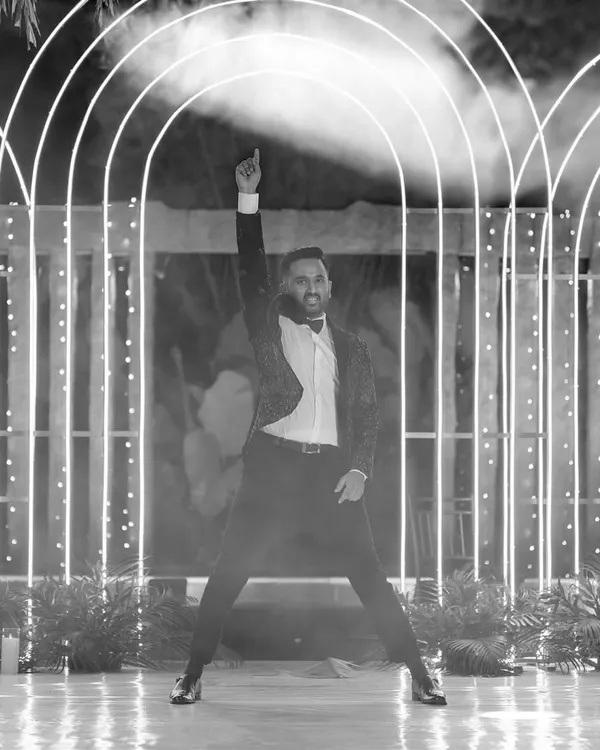 A groom strikes a pose in a black-and-white shot, part of a larger performance telling the couple's love story.