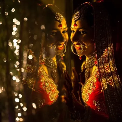 A timeless bridal portrait using reflection to create a classic, layered look. I focus on using available light, like these fairy lights, to add a magical bokeh effect and highlight the bride's joyful expression on her wedding day.