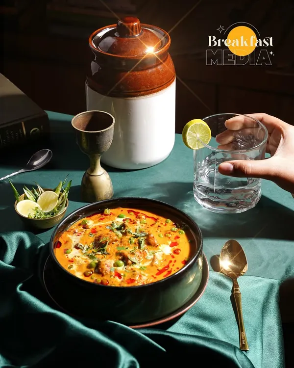 This shot captures the rich, inviting feel of a restaurant's signature curry. I use dramatic lighting and lifestyle elements, like a hand reaching for a drink, to create a scene that makes you want to be there. This is what professional restaurant photography is all about.