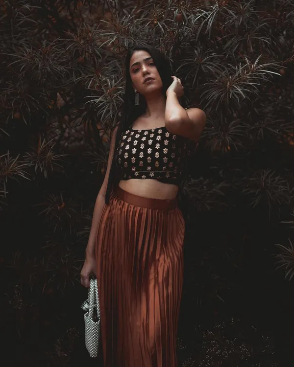 A portrait that uses a dark, natural background to create a moody and enchanting atmosphere. The color grading enhances the earthy tones, making the subject stand out with a quiet intensity.