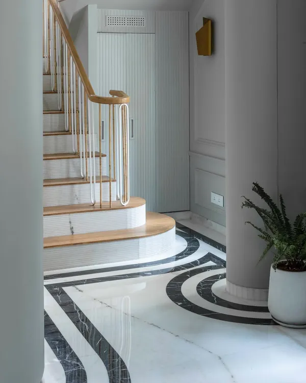 The staircase at Summer Haus is the metaphorical spine of the home, its elegant curve and marble detailing creating a sense of rhythm as it connects the public and private floors. The custom brass and wood railing is a testament to our focus on bespoke craftsmanship.